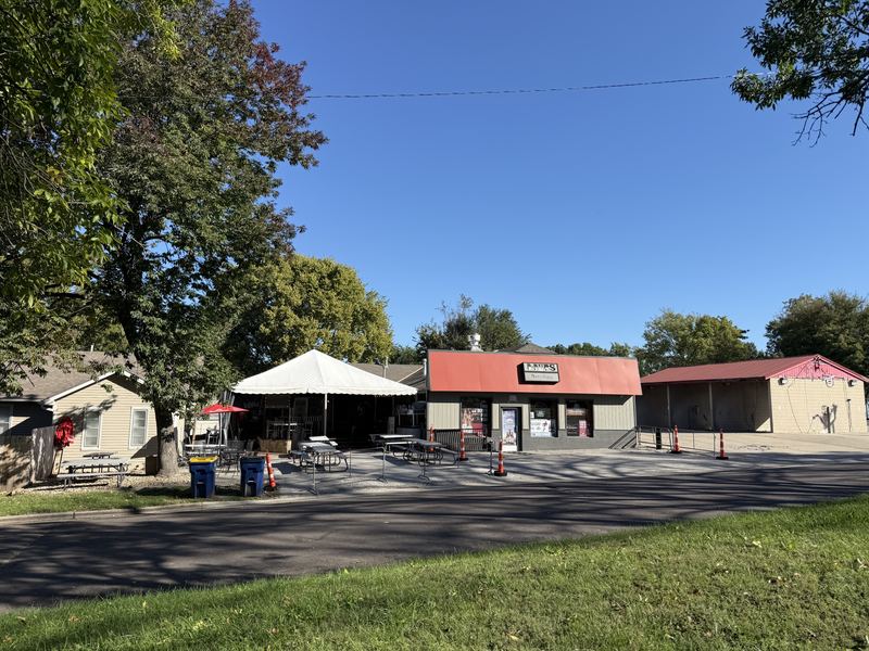 DDubs on a sunny day, a red-roofed building with a white tent and picnic tables out front under big shade trees